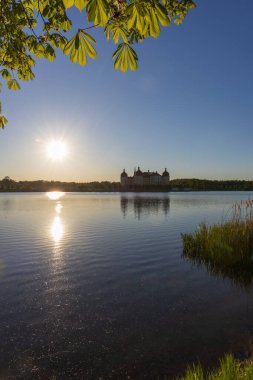 Gün batımında Moritzburg Şatosu Castle Pond 'un yüzeyine yansıyor. Altın güneş ve kestane yaprakları ön planda. Tarihi dönüm noktası.