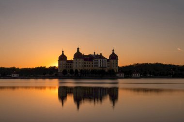 Altın saat boyunca Barok Moritzburg Kalesi 'nin sakin ve simetrik bir görüntüsü. Göletin ada şatosu, yumuşak bir ışıkla aydınlanır.