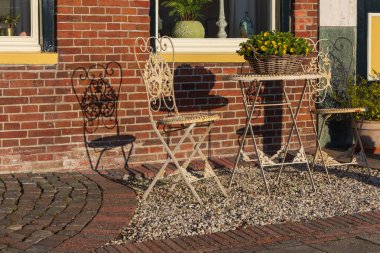 Bedum 'da geleneksel bir evin tuğla duvarında beyaz metal sandalyelerin zarif gölgeleri. Hollanda, Groningen 'de bir bahar sabahının ayrıntıları.