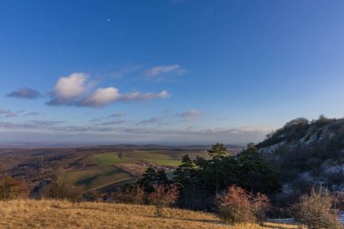 Palava tepelerinden vadiye kadar kış manzarası. Mavi gökyüzünün altında tarlalar ve ormanlar var. Güney Moravya, Çek Cumhuriyeti 'nde güneşli bir gün.
