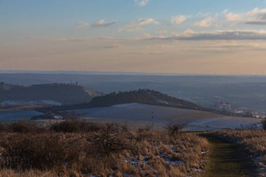 Panoramic view from Table Mountain to Mikulov and Holy Hill in winter. Picturesque Palava landscape with wind turbines on the horizon at sunset.