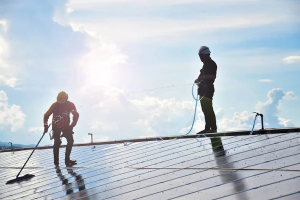 Photovoltaic panels installed on the roof of the building to use clean and green energy from the sunlight. The workers are washing and cleaning the surface of them because of there are the pigeon\'s droppings and dust.