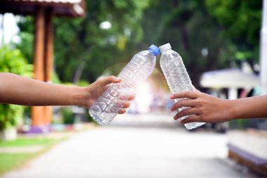 Boş plastik şişeler ve el altında bükülmüş plastik şişeler, küresel ısınmayı azaltma, kirliliği azaltma ve dünyanın dört bir yanındaki çevreyi kurtarma kavramı.