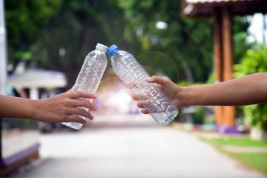 Boş plastik şişeler ve el altında bükülmüş plastik şişeler, küresel ısınmayı azaltma, kirliliği azaltma ve dünyanın dört bir yanındaki çevreyi kurtarma kavramı.