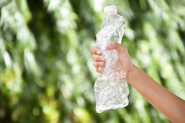 Boş plastik şişeler ve el altında bükülmüş plastik şişeler, küresel ısınmayı azaltma, kirliliği azaltma ve dünyanın dört bir yanındaki çevreyi kurtarma kavramı.