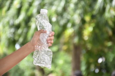 Boş plastik şişeler ve el altında bükülmüş plastik şişeler, küresel ısınmayı azaltma, kirliliği azaltma ve dünyanın dört bir yanındaki çevreyi kurtarma kavramı.