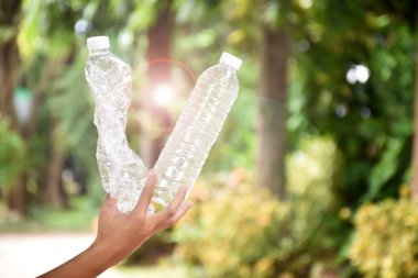 Boş plastik şişeler ve el altında bükülmüş plastik şişeler, küresel ısınmayı azaltma, kirliliği azaltma ve dünyanın dört bir yanındaki çevreyi kurtarma kavramı.