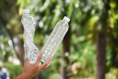 Boş plastik şişeler ve el altında bükülmüş plastik şişeler, küresel ısınmayı azaltma, kirliliği azaltma ve dünyanın dört bir yanındaki çevreyi kurtarma kavramı.