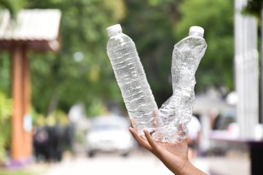 Boş plastik şişeler ve el altında bükülmüş plastik şişeler, küresel ısınmayı azaltma, kirliliği azaltma ve dünyanın dört bir yanındaki çevreyi kurtarma kavramı.