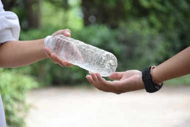 Boş plastik şişeler ve el altında bükülmüş plastik şişeler, küresel ısınmayı azaltma, kirliliği azaltma ve dünyanın dört bir yanındaki çevreyi kurtarma kavramı.