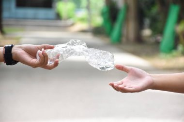 Boş plastik şişeler ve el altında bükülmüş plastik şişeler, küresel ısınmayı azaltma, kirliliği azaltma ve dünyanın dört bir yanındaki çevreyi kurtarma kavramı.