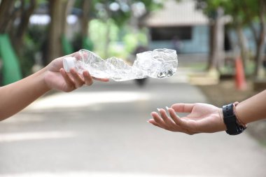 Boş plastik şişeler ve el altında bükülmüş plastik şişeler, küresel ısınmayı azaltma, kirliliği azaltma ve dünyanın dört bir yanındaki çevreyi kurtarma kavramı.