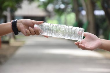 Boş plastik şişeler ve el altında bükülmüş plastik şişeler, küresel ısınmayı azaltma, kirliliği azaltma ve dünyanın dört bir yanındaki çevreyi kurtarma kavramı.