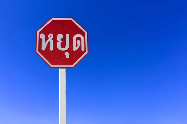 Traffic sign; Isolated STOP sign on pole with clipping paths. Thai language in photo is \'STOP\' in English.