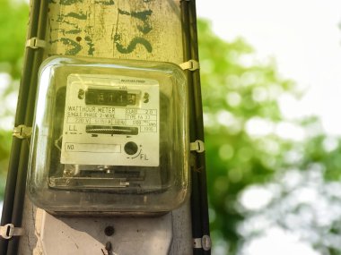 Küçük bir ev elektrik sayacı, aylık elektrik tüketimini kaydetmek için bir elektrik direğine asılır. Yumuşak ve seçici odak.