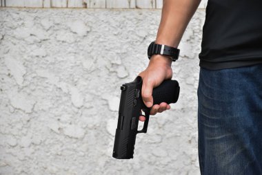Otomatik siyah 9 mm 'lik tabanca hedefe, soygun konseptine, gangstere, güvenliğe ve dünya çapında atış sporlarına yönelik tetiği çekmeye hazır..