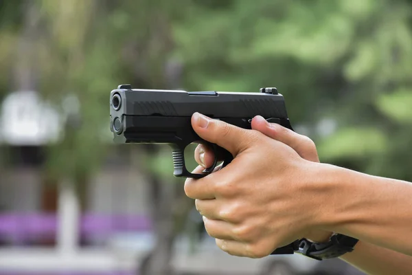 Automatic black 9mm pistol in hands ready to pull the trigger aiming to destination , concept for robbery, gangster, security and shooting sports around the world.