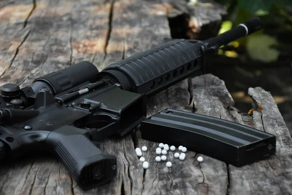 木制地板上的黑色长管自动气枪或Bb枪 带有白色塑料子弹 软性和选择性重点 — 图库照片