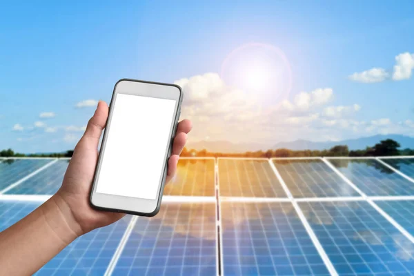 Mockup of mobile phone in hand with photovoltaic panels which installed on the roof of the building to store and use the sunlight energy from the nature in daily life, sustainable and environmental friendly energy concept.