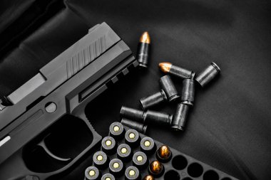 Otomatik siyah 9 mm tabanca ve siyah deri arka planda mermi kovanları, soygun konsepti, bodygaurd, mafya, gangster, güvenlik ve dünya çapında güvenlik. kırpma yolları.