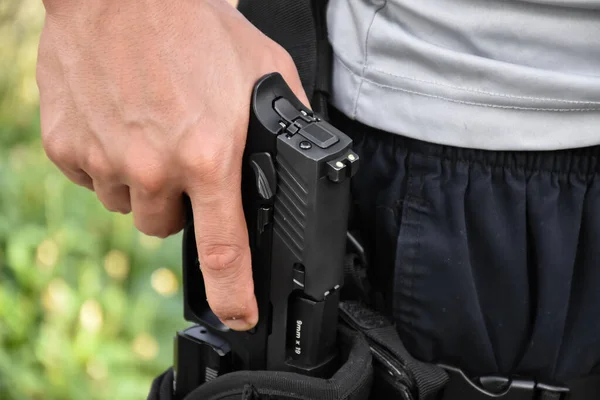 Otomatik 9mm 'lik tabanca kılıfına dayanıyor. Çekilmeye ve hedefe ateş etmeye hazır. Güvenlik mesleği kavramı ve dünya çapında atış sporu..