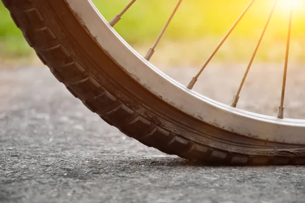 stock image Close up view of bike which has flat tire and parked on the pavement, blurred background. Soft and selective focus on tire.