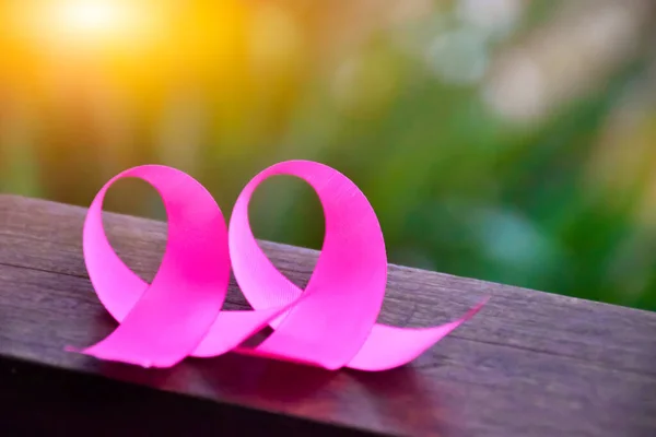 木製のテーブルの上にピンクのリボン 日光や背景のぼやけ 世界中の乳がんの意識のための概念 ピンクリボンに柔らかく選択的な焦点 — ストック写真