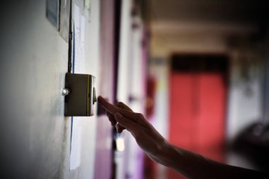 Ev sahibi evin duvarındaki elektrik düğmesini kapatıyor. Tasarruf yapmak ve çevreyi korumak için. Yumuşak ve seçici odak.