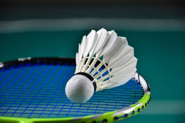 Badminton raketi ve badminton kortunda beyaz badminton topu. Mekik siki üzerine yumuşak ve seçici odaklanma.