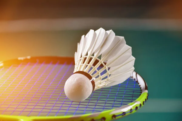 Badminton racket and white badminton shuttlecock on badminton court. soft and selective focus on shuttlecock.