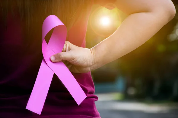 ピンクの紙のリボンは 女性の手の中に保持し 世界中の缶から病気である女性の乳癌と戦うために支援するための概念 柔らかくて選択的な焦点 — ストック写真