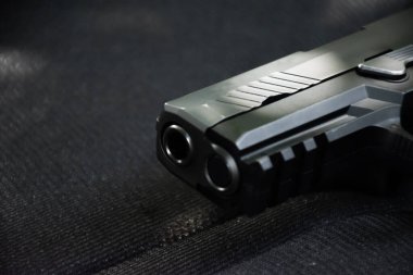 Siyah deri üzerinde 9mm 'lik siyah tabancanın yakın görüntüsü..