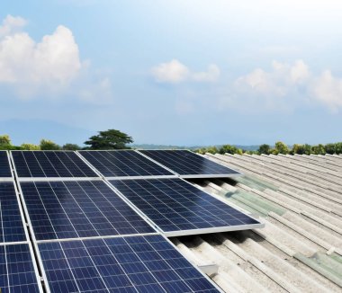 Binanın çatısına yerleştirilmiş fotovoltaik paneller, bulutlu ve manzaralı arka plan 