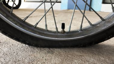 Düz ve kırsal yolun kenarındaki kaldırımda duran ve yeniden düzleştirilmeyi bekleyen bir motosiklet tekerleği. Yumuşak ve seçici odak.