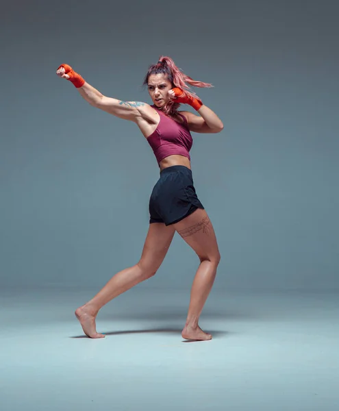 Lutador feminino treina em ataduras de boxe em estúdio em fundo cinza. — Fotografia de Stock