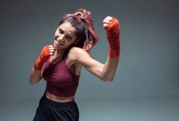 Lindo lutador menina em bandagens de boxe faz um uppercut no estúdio isolado em fundo cinza. Força e motivação — Fotografia de Stock