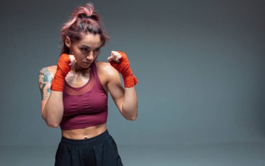 Atletik kız boks antrenmanları gri arka planda izole edilmiş bandajlarla yapılıyor. Kadınların spor ve motivasyon konsepti