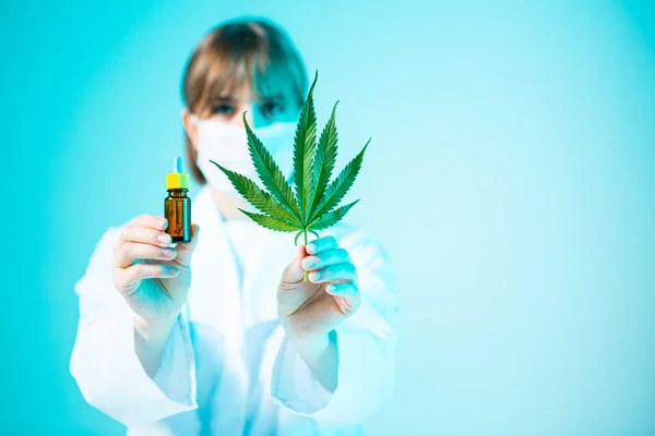 Pot modèle en verre avec produit de cannabis CBD et feuille de chanvre entre les mains d'une femme médecin en lumière au néon — Photo