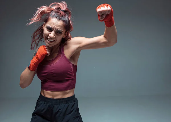 Cool girl fighter treina em bandagens de boxe em estúdio isolado em fundo cinza. Desporto feminino e conceito de motivação — Fotografia de Stock