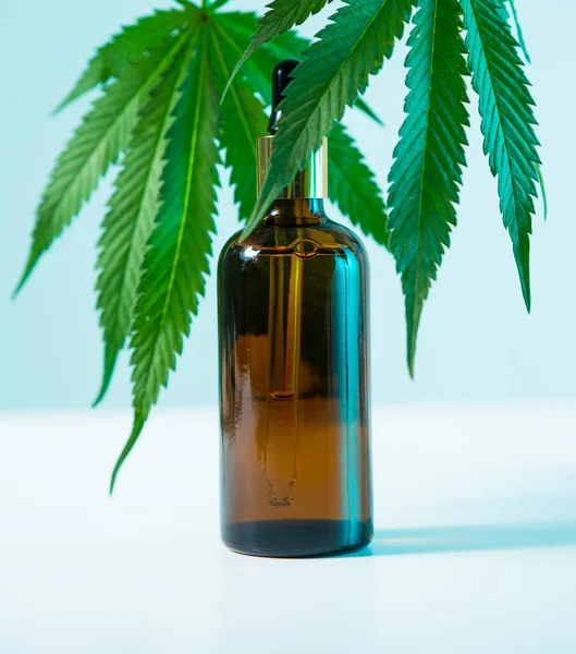 CBD製品と麻の葉を持つガラス瓶ネオンブルーライト、クローズアップ — ストック写真