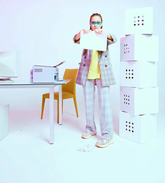 Κομψή Ασιάτισσα υπάλληλος γραφείου σκίζει ένα φύλλο χαρτί κοντά σε εκτυπωτή και κουτιά. Έγχρωμο φως νέον — Φωτογραφία Αρχείου