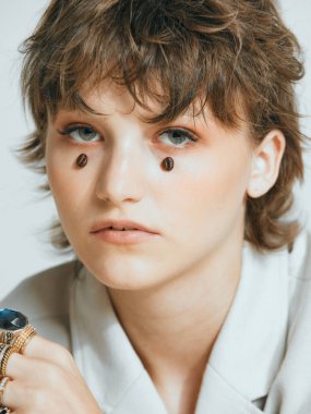 Genç kızın yüzündeki kahve çekirdekleri gözyaşı gibi, şık kısa saç kesimi, bayan stüdyo portresi