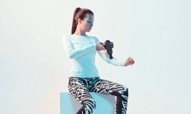 Atletik, genç, esmer kadın. El masajcısı, el yapımı, parlak ışıklı masaj aleti.