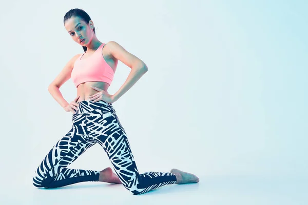 Sportlich geschnittenes weibliches Model in stylischer Sportbekleidung posiert in neonfarbenem Studiolicht. Werbefoto mit Kopierraum — Stockfoto