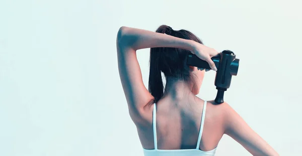Percussie massager, jonge brunette vrouwelijke masseren schouder in neon studio licht, therapie voor gewrichtspijn verlichting — Stockfoto