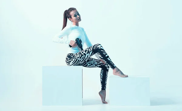 Spor giyim sektöründe genç bir bayan. El bilgisayarıyla masaj yapıyor. Neon ışığı altında masaj tabancasıyla.