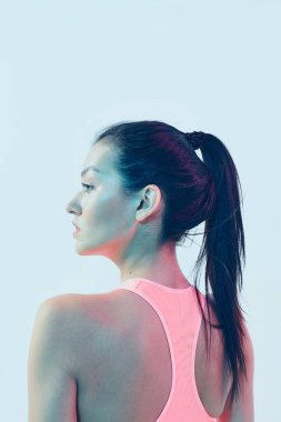 Pembe spor bluzlu güzel esmer kız. Stüdyo ışığı altında poz veriyor.