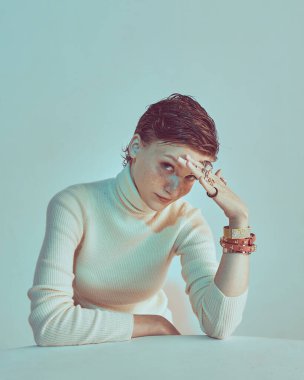 Kızıl saçlı, kısa saçlı, kısa saçlı, stüdyo ışığı altında poz veren genç bir kız.