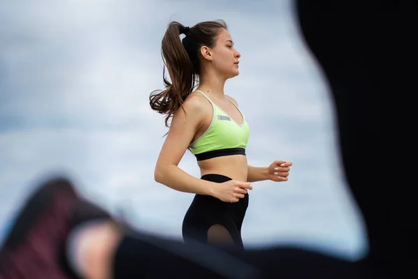 Correr maratón chica atlética, mujer corriendo al aire libre en el entrenamiento de grupo, fotografía de cerca — Foto de Stock