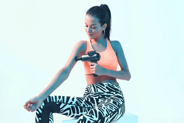 Atletik, genç, esmer kadın. El masajcısı, el yapımı, parlak ışıklı masaj aleti.